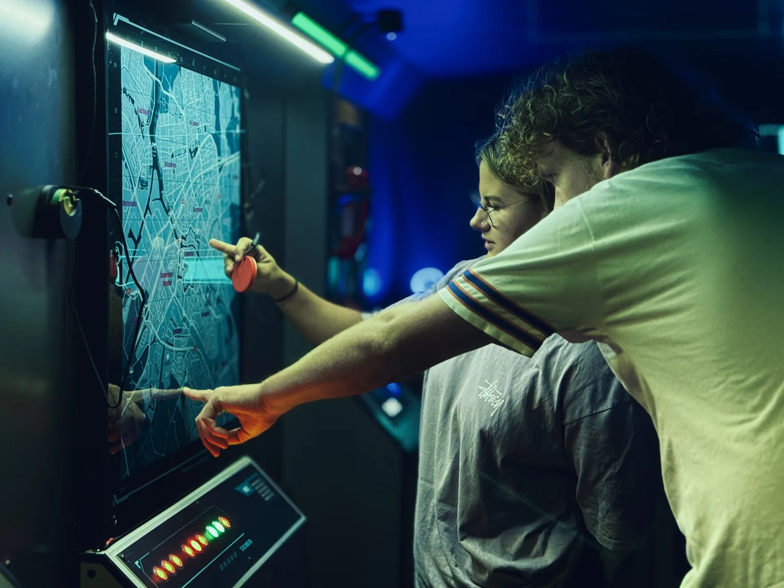 Twee spelers wijzen naar een verlicht stadsplattegrond-scherm in een escaperoom